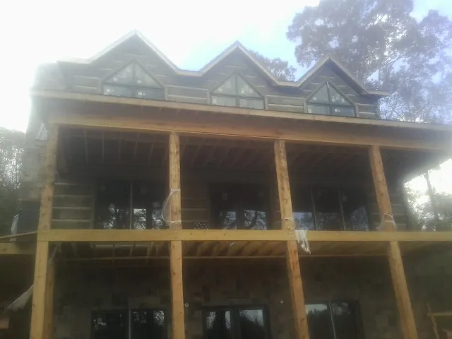 Dormers and porch framing on a large log home under construction — Roof Coating work by our crew in Francestown