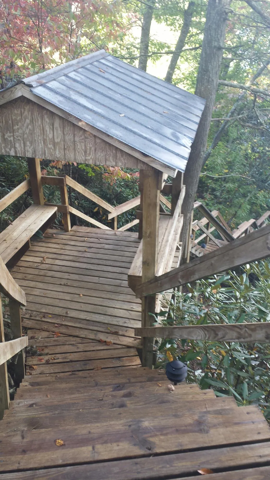 Metal roofed shelter over wooden steps on a wooded walkway — Skylight Repair & Installation work by our crew in Francestown