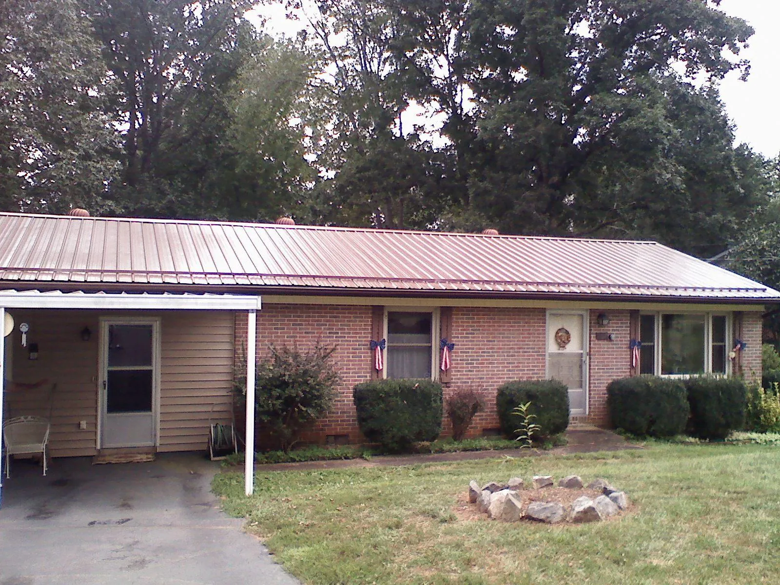 Bronze metal roof and carport on a brick ranch home — Roof Repair work by our crew in Francestown