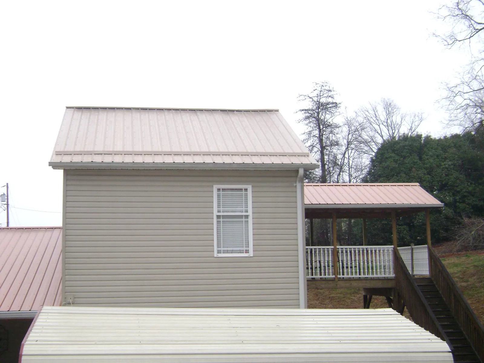Tan metal roofs on a two story addition and attached porch, from a Roof Replacement job in Francestown