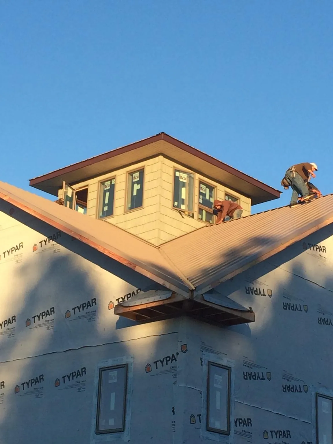 Roofers working around a rooftop cupola on a new metal roof at sunset — Roof Waterproofing in Francestown by Roofing Brothers